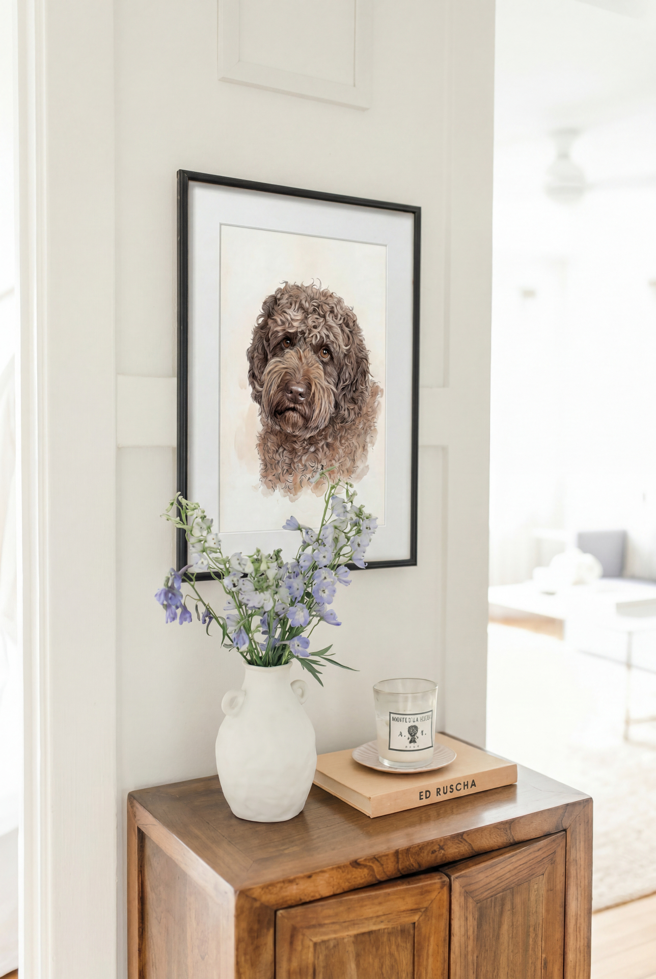 Innrammet hundeportrett hengende i gangen over en kommode med blomster